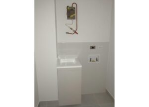 Small laundry alcove with a white utility sink and washer hookups on the wall.