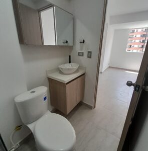 Compact modern bathroom with a toilet, wooden vanity with a vessel sink, and a mirrored cabinet.