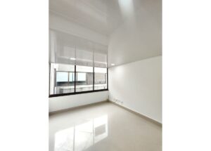 Bright empty office room with large window, white walls, and a glossy tiled floor bathed in natural light from outside glass panes.