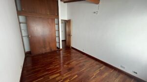 Empty room with dark wood floors, a large built-in wooden wardrobe, and an open door to a hallway/adjacent room.