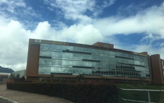 Facade of a modern brick and glass office building under a blue sky with clouds.