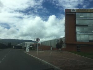 Road leading to a modern brick office building with glass windows on the right, cloudy blue sky above and a signpost in the foreground.