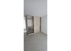 Floor-to-ceiling wardrobe with sliding doors, open section showing a hanging rail and shelves in a bare, light-gray room.