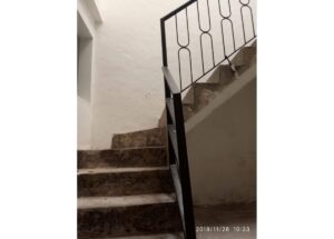 Worn concrete stairs with a black metal railing in a white-walled stairwell; timestamp 2019/11/28 10:23.