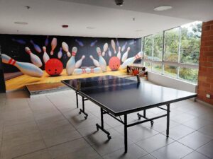 Indoor game room with a ping-pong table and a bowling-themed mural on the wall behind it.
