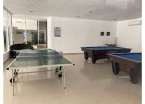 Indoor recreation room with a green ping-pong table and two pool/billiards tables nearby