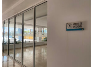 Hallway with tall glass sliding doors leading to an event room; sign on the wall reads 'Salón de Eventos'.