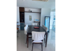 Contemporary dining room with a dark wood table, six white-covered chairs, and a red centerpiece plate.