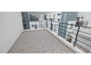 Balcony with patterned tile flooring and dark metal railing overlooking modern white apartment buildings.