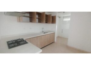 Modern kitchen with white countertops, light wood base cabinets, a gas cooktop on an island, and a sink along the wall.