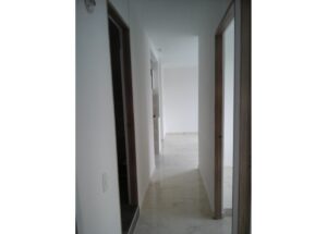 Bright hallway in a modern home with white walls, marble floor, and open doorways along both sides.