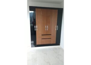 Built-in wardrobe with a black frame and five wood-toned doors and two central drawers under the middle doors