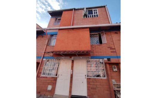 Two white doors at the base of a red-orange brick building with barred windows and a blue horizontal stripe across the façade