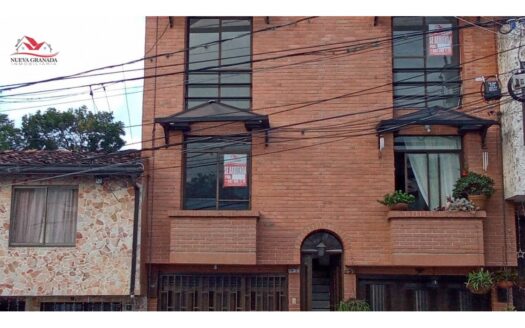 Brick three-story townhouse with rental signs in the windows and a logo in the top-left corner reading 'Nueva Granada Inmobiliaria'
