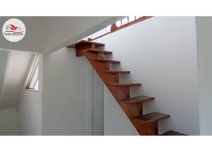 Interior view of a wooden floating staircase with open risers against white walls in a bright modern room.