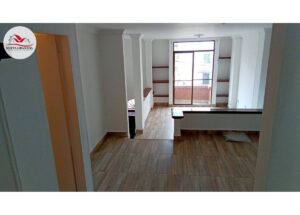 Bright living area with white walls, built-in shelves, and a glass balcony door at the far end.