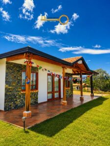Sunny single‑story house with a stone façade, wooden columns, and a tiled porch decorated with international flags.