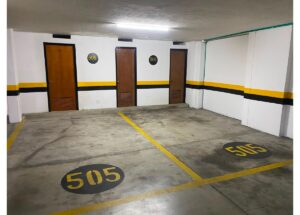 Underground parking area with yellow-lined spaces and three doors along the wall; circular floor markers read 505.