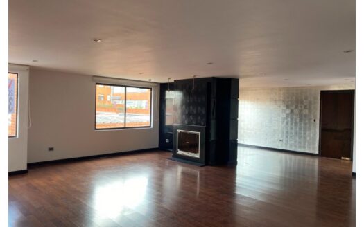 Empty living room with dark wood floors, a black fireplace, and large windows letting in light.